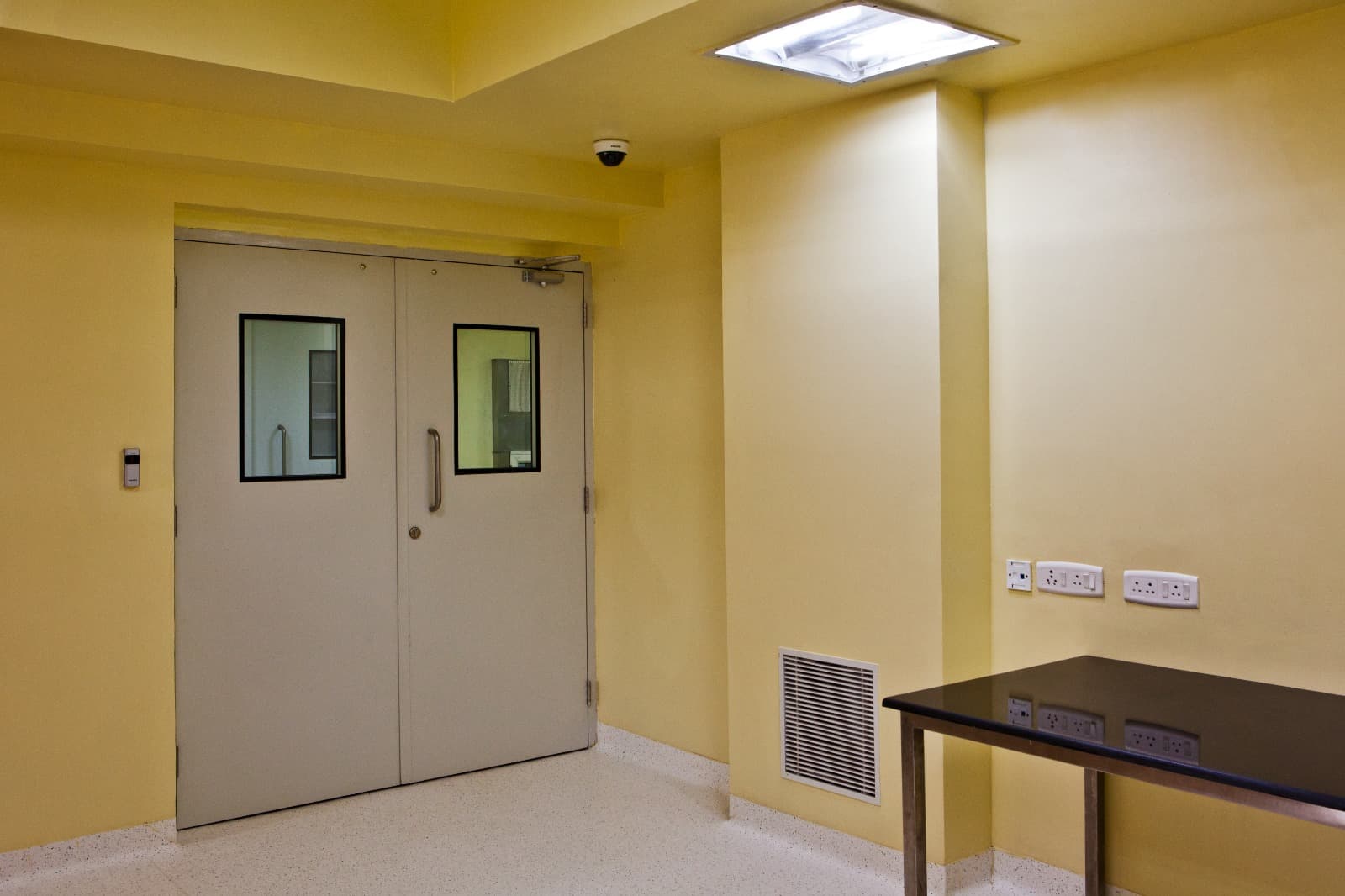 Cleanroom gowning area with interlocking grey GMP doors and CCTV monitoring