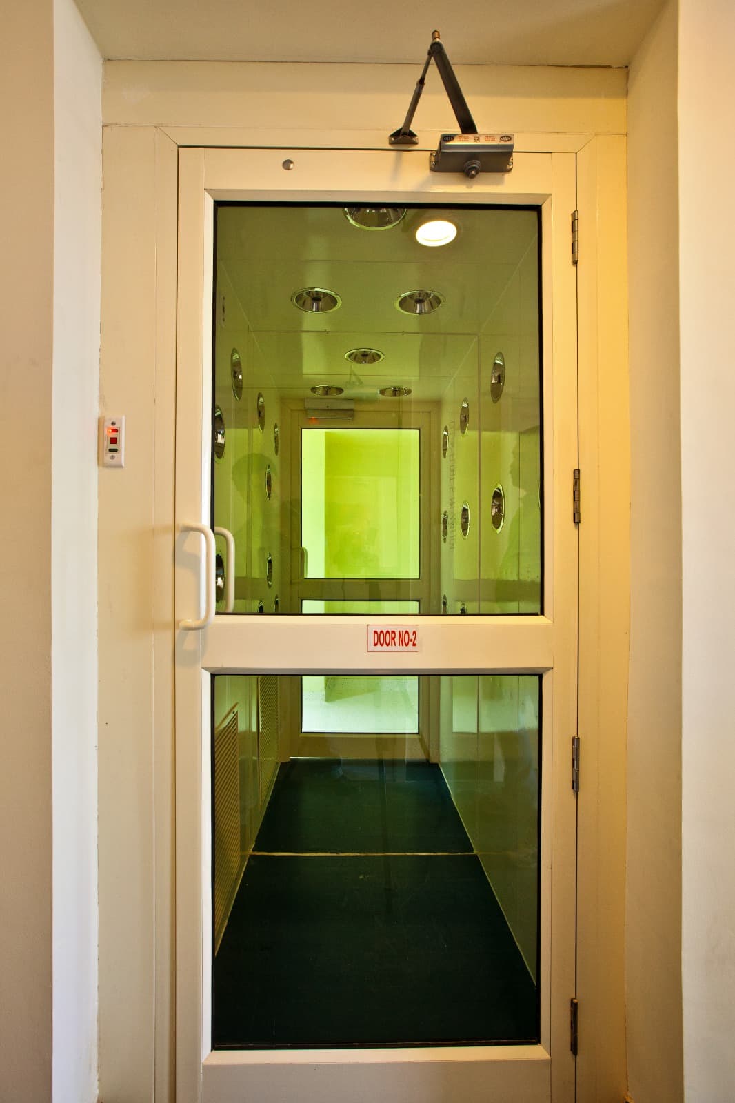 Cleanroom air shower with a green-glass interlocking door at a personnel entry
