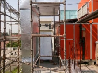 Insulated vertical GI duct riser being installed behind access scaffolding