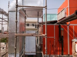 Insulated GI duct riser erected on scaffolding beside a rooftop unit