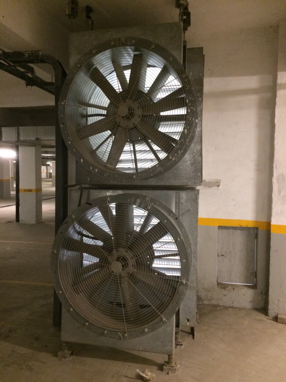 Twin high-capacity axial ventilation fans on spring mounts in a basement car park