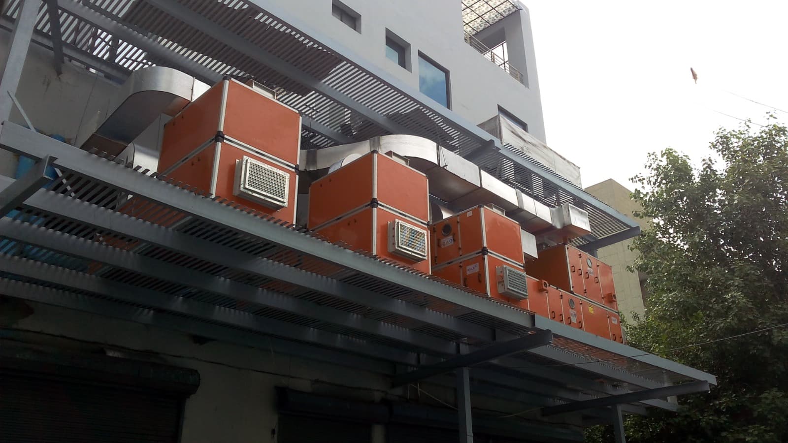 Orange double-skin AHUs and TFA units connected to ducting on a service deck