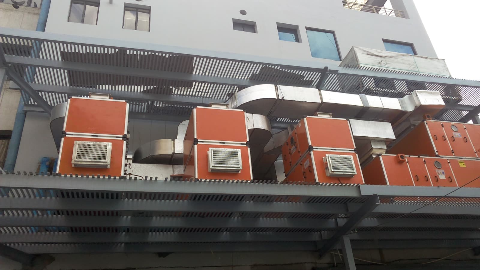 Bank of orange AHUs and TFA units with insulated ducting on a rooftop