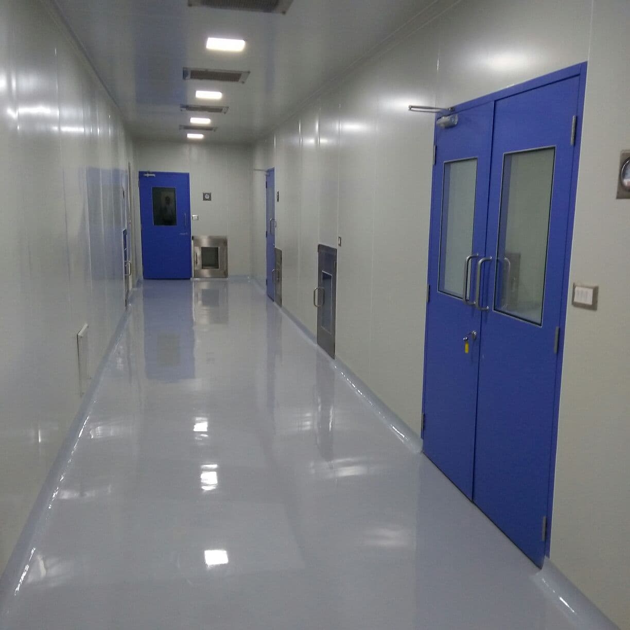 Pharma cleanroom corridor with blue GMP double doors, epoxy flooring and dynamic pass boxes