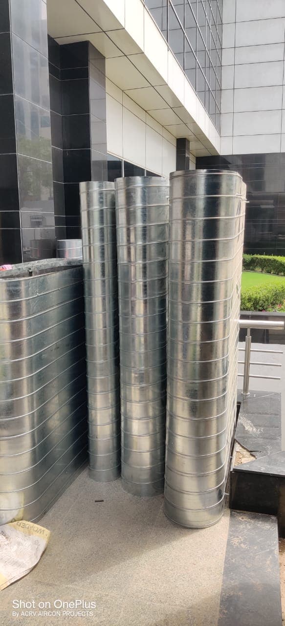 Spiral round GI ducting sections stacked at a building entrance