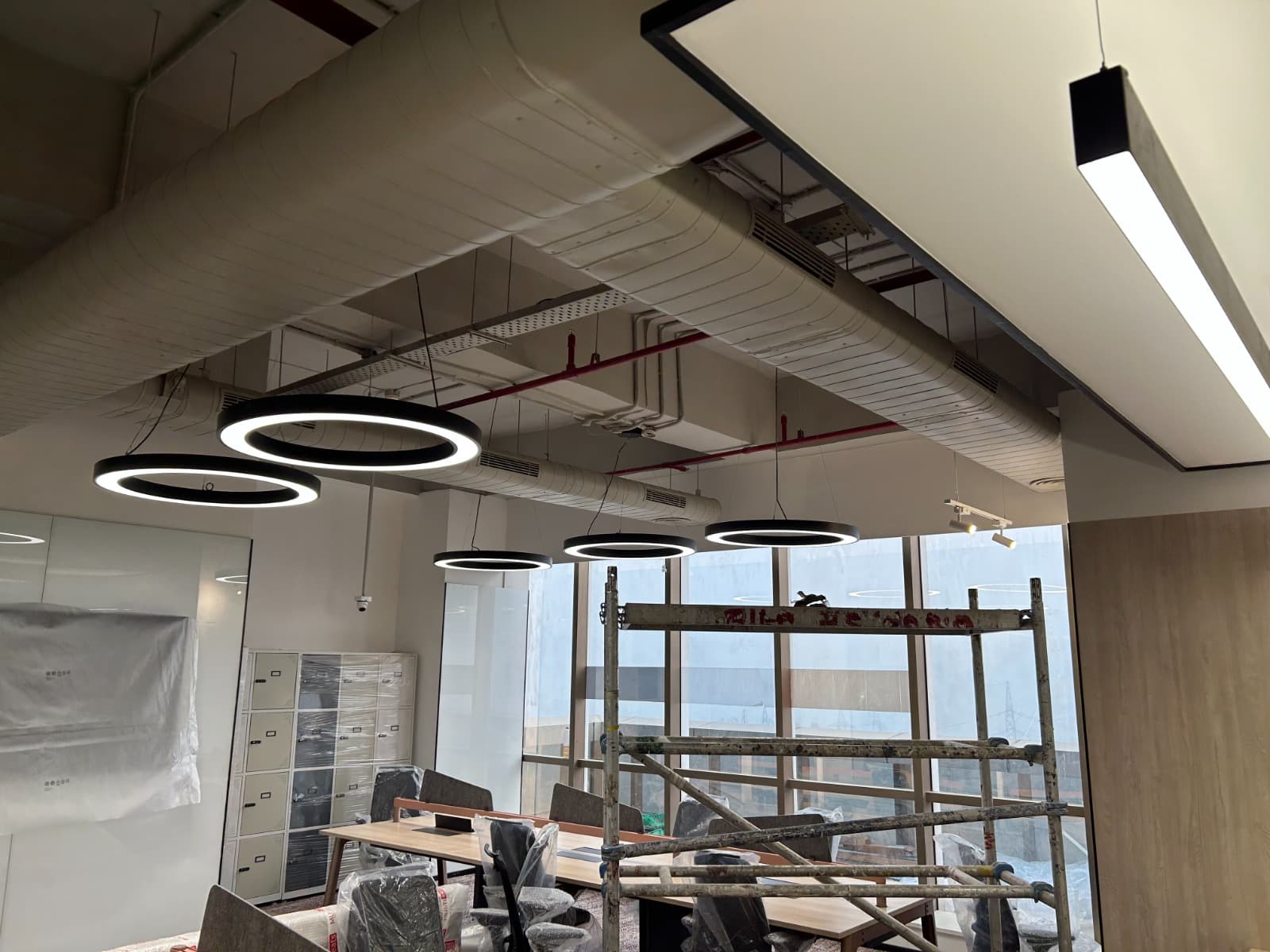Meeting room with exposed spiral ducting, ring pendant lights and linear diffusers