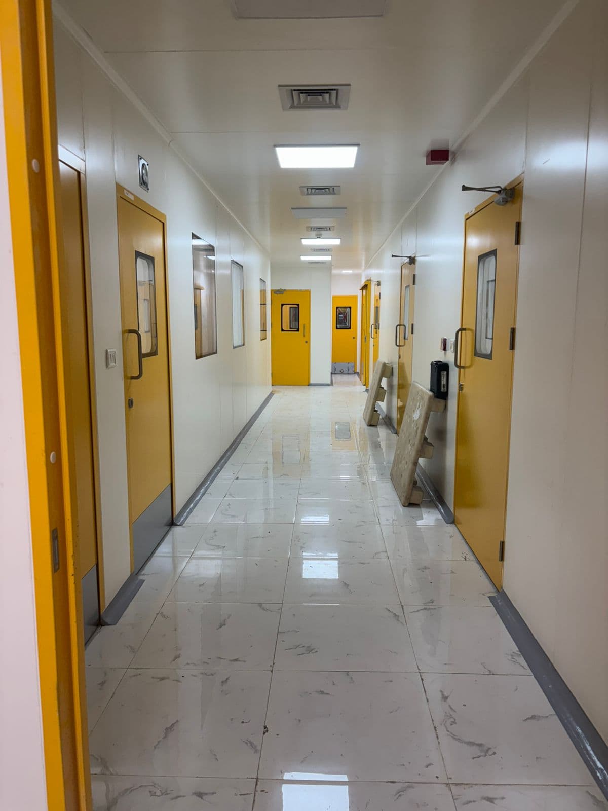 Cleanroom corridor with yellow GMP doors and polished vitrified flooring