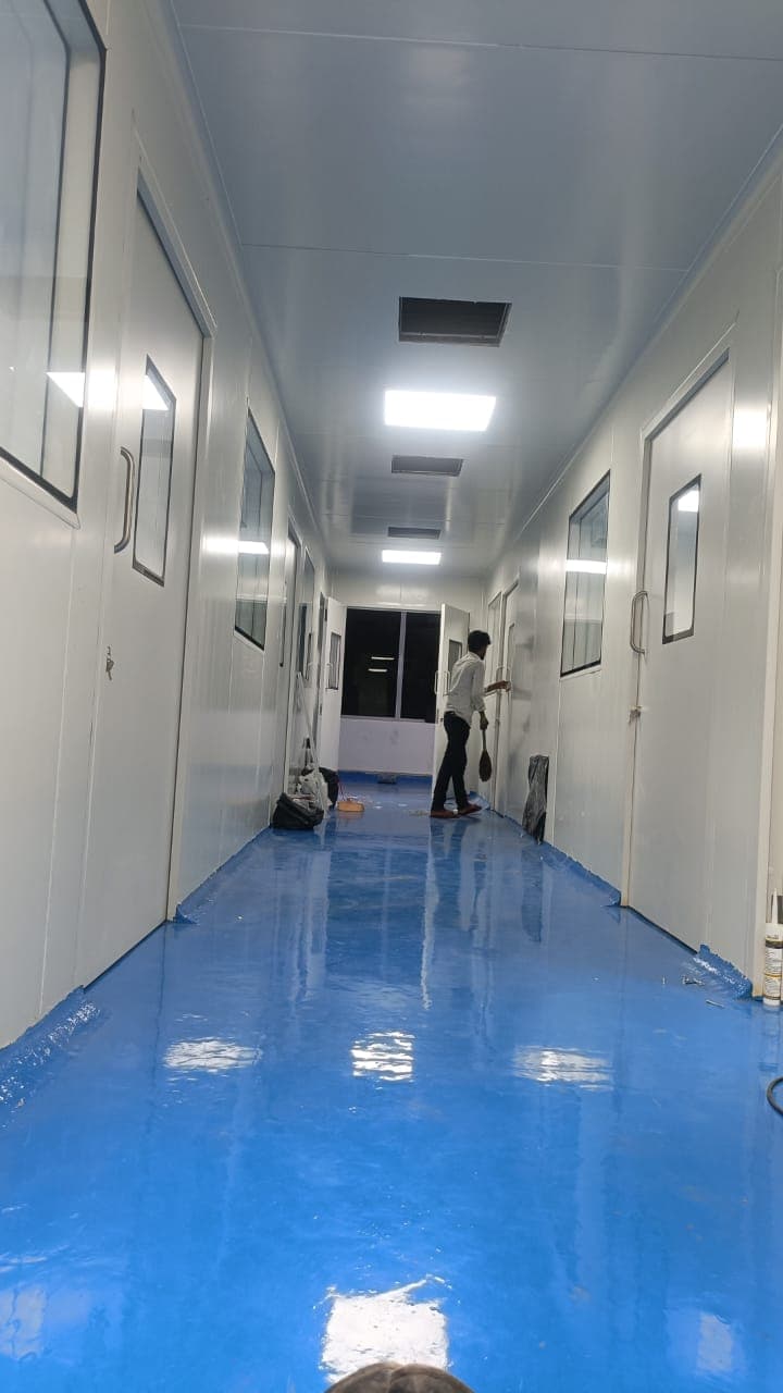 Cleanroom corridor under fit-out with blue self-levelling epoxy floor being applied