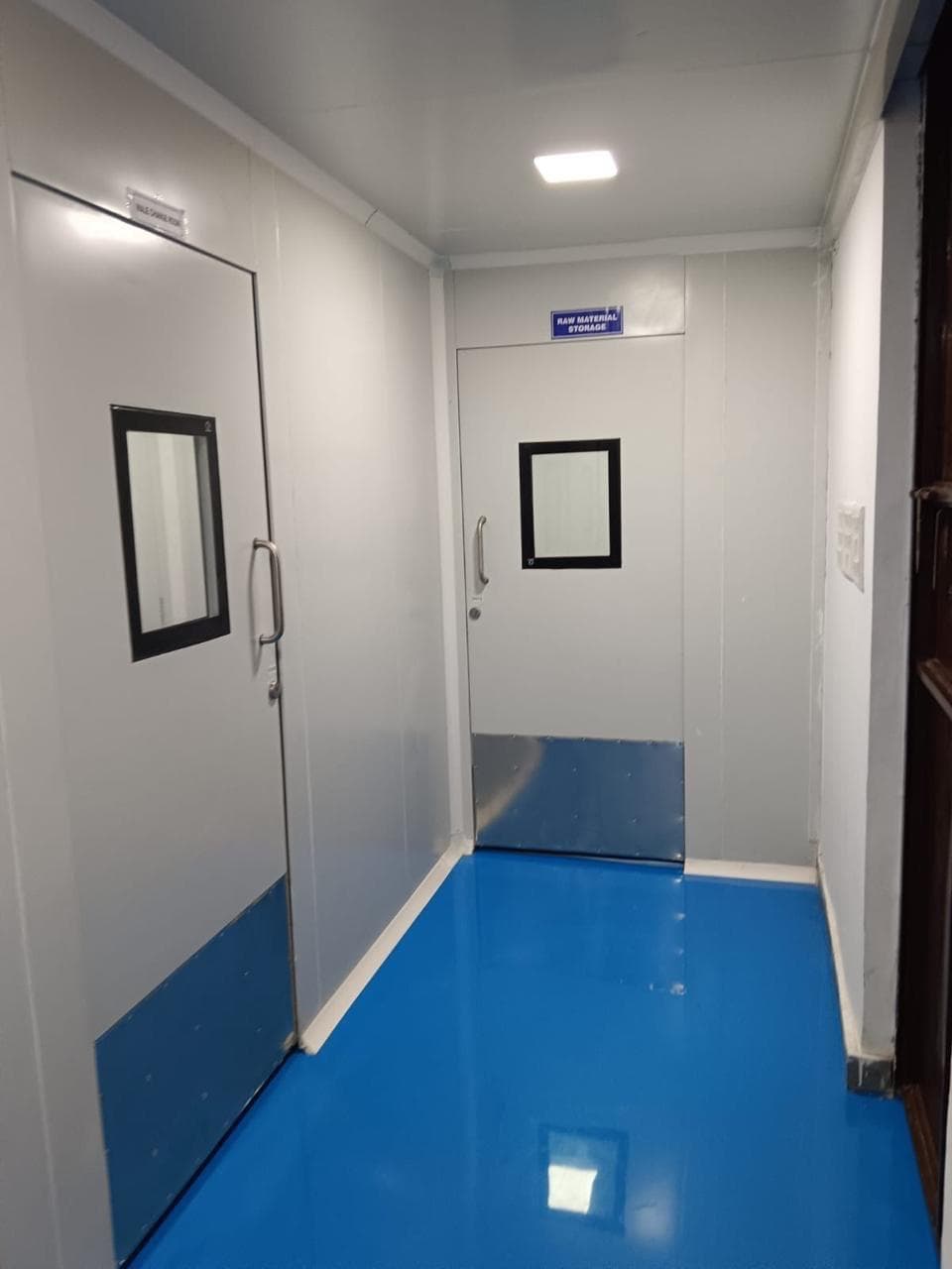 Cleanroom change-room and raw-material-storage entries with blue epoxy floor
