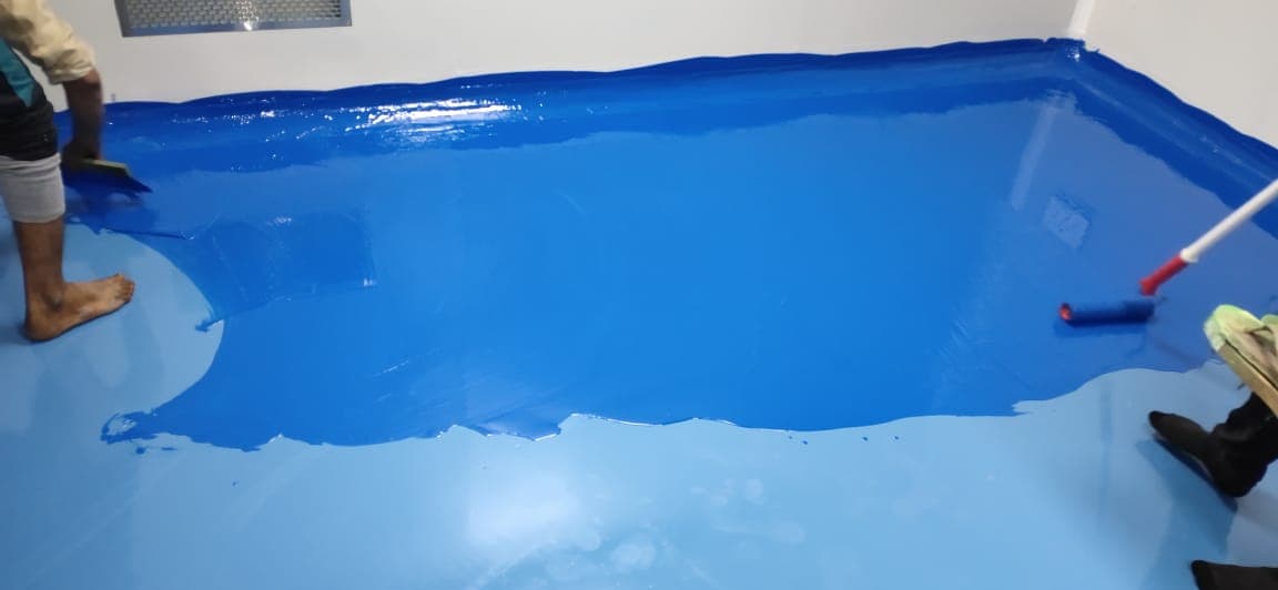 Blue epoxy floor coating being laid across a cleanroom