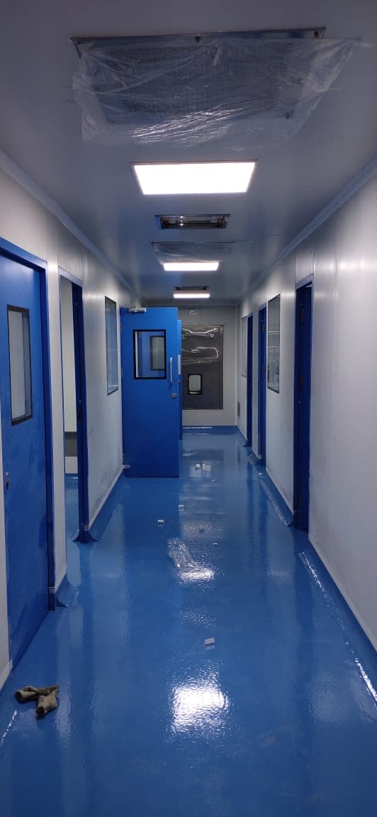 Cleanroom corridor with blue epoxy floor, blue GMP doors and an air shower