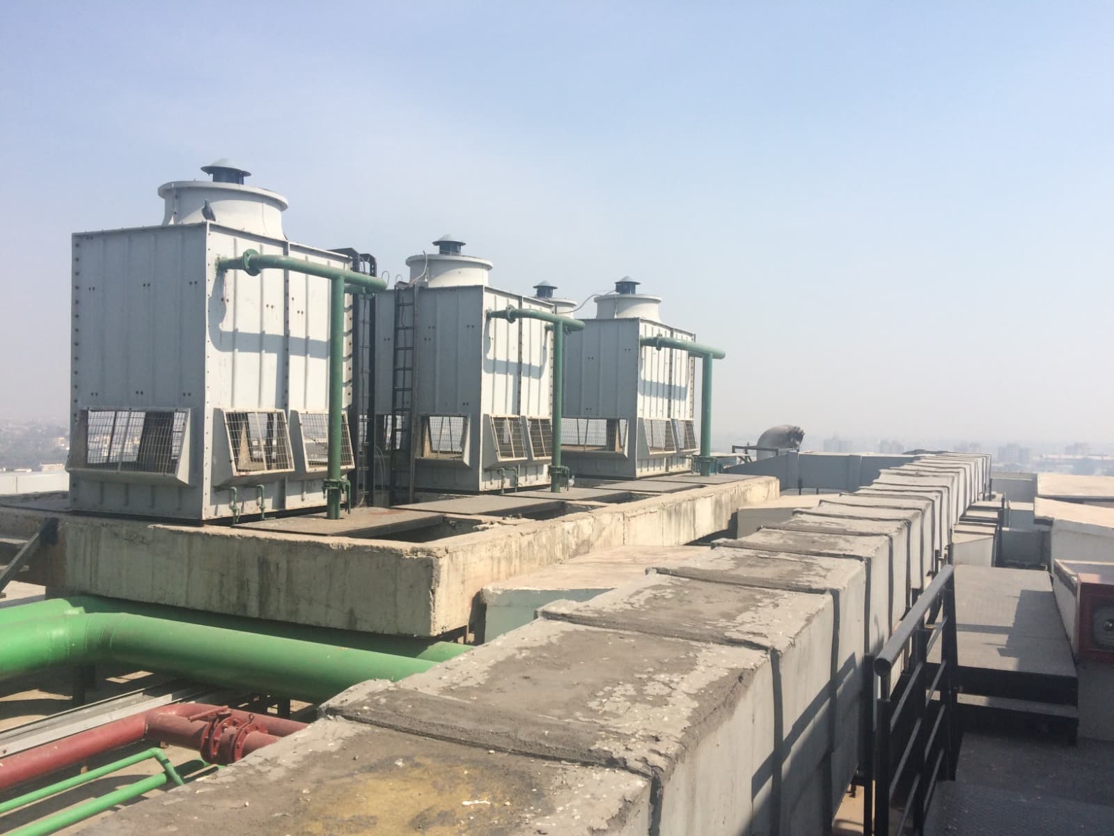 Rooftop FRP cooling towers with green condenser-water piping headers