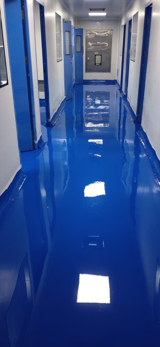 Cleanroom corridor with a mirror-finish blue epoxy floor leading to an air shower